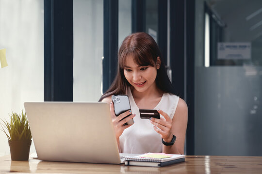 Woman enjoy with online shopping application and looking at credit card for fill number to payment