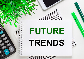 Calculator, green plant, telephone, marker, notebook with the text FUTURE TRENDS on the desktop. Flat lay.