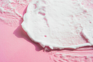 Textured smear of white creamy foam on pink background. Abstract swatch of cosmetics facial, body care. Beauty selfcare banner.
