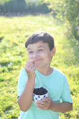niño feliz con una taza llena de moras al atardecer - 455137611