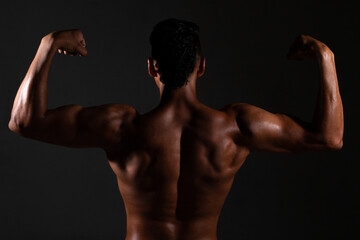 Fototapeta na wymiar Bodybuilder showing his back and biceps muscles, personal fitnes.Brown-skinned man