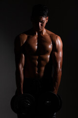 Fototapeta na wymiar Latin and muscular man using weights. Shirtless man lifting weights. man muscles marked.