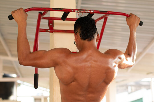 Latin man doing a lot of strength. concept of strong and muscular man. pull-ups in urban gym