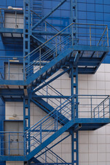Modern building  with a fire escape. Blue Fire Escape Stairs on the building. Fire escape ladder zigzagging....