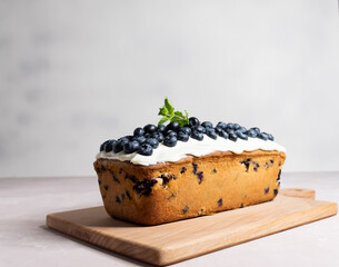 Blueberry cake with cream cheese ganache on the wooden board on the grey background