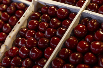 Ripe juicy cherries in boxes on the market. Close-up. Health and vitamins from nature.