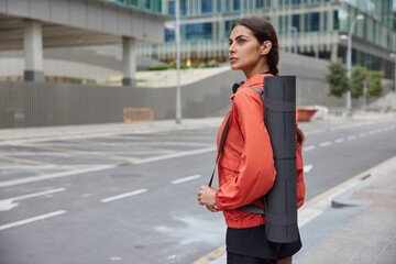 Horizontal shot of sportswoman does aerobic exercises to stimulate breathing rate to have stronger heart walks outside in urban setting going to burn calories after cheat days. Daily exercising © WHstudio Leushin N