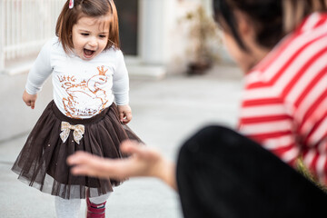 Cute, little toddler girl walking towards her mom