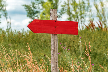 Handmade wooden direction sign in countryside meadow with blank signage as copy space