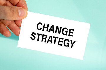 businessman's hand holding paper business card with text change strategy, closeup light blue background