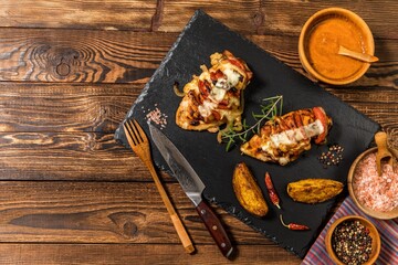 Baked roasted hasselback chicken stuffed with cheese and tomato. Portions of meat on the table. Keto diet. Baked chicken breast.