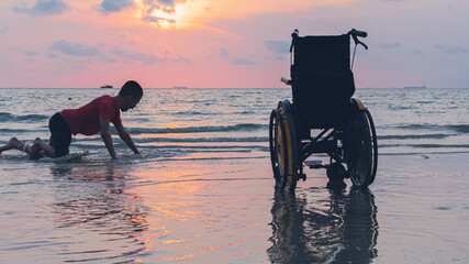 Happy disabled teenage boy and wheelchair playing and relaxing with parent, Activity outdoors with father on the beach background, People having fun and diverse family concept.