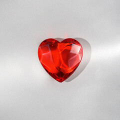 Creative concept of love. Glass red heart on a gray background.
