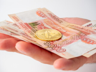 a man's hand holds Russian banknotes and bitcoin. The concept of earning and mining