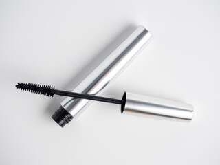 mascara in a silver tube lies on a white background. A brush for applying mascara. Cosmetology, self-care. Women's beauty