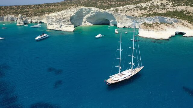 Arial drone video of sail boat anchored in Kleftiko a rock formation bay visited by sail boats and yachts with turquoise crystal clear sea and caves, Sea Meteora of Greece, Milos island