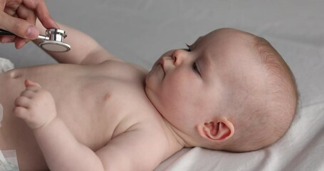 Paediatrician examining baby kid, listening to patient heart with stethoscope, close up view. Cute infant in diaper lying, pass heartbeat check up. Medicine and healthcare, general checkup concept