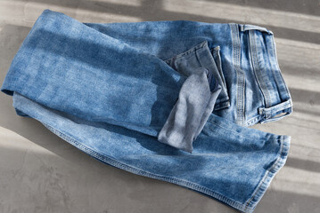 a blue light folded jeans on a grey background. Sunlight