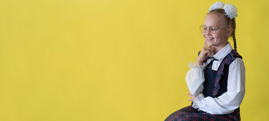 A child in a school uniform on a yellow background. A girl with round glasses