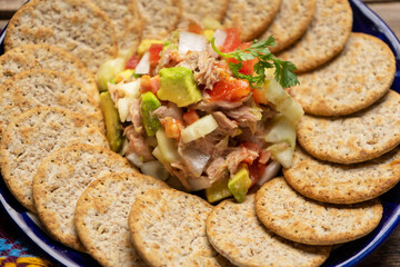 Tuna salad with avocado and cucumber on wooden background