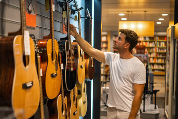 Man picking guitar in music shop