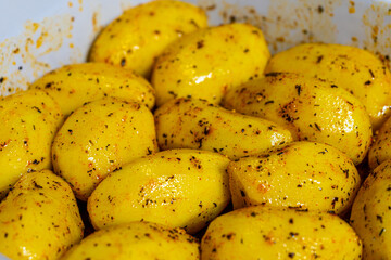 Raw potatoes with spices prepared for baking in oven