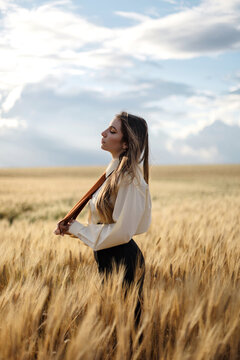 Stylish model in wheat field under cloudy sky