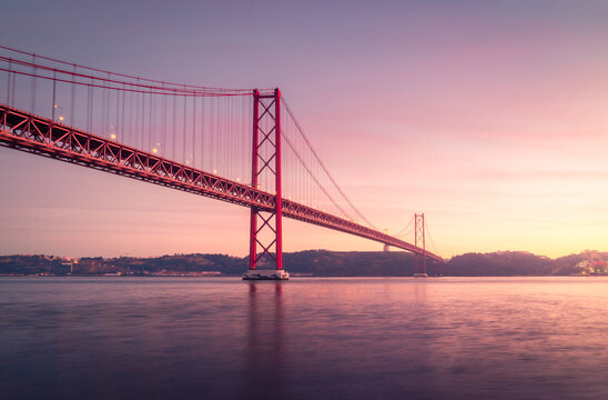 Modern bridge over river at sunset