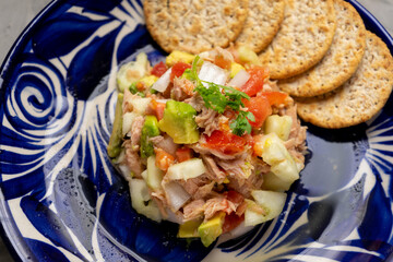 Tuna salad with avocado and cucumber on grey background