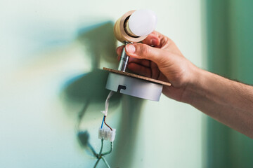 Hands holding a wall lamp. Light for the bedroom.