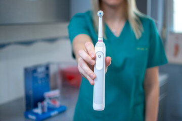 Female dentist's hand holding electric teethbrush at dental office