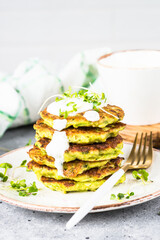 Zucchini pancakes with spinach, hepbs and parmesan cheese, served with sour cream or yogurt. Healthy food.