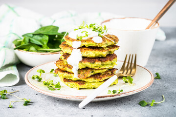 Zucchini pancakes with spinach, hepbs and parmesan cheese, served with sour cream or yogurt. Plant-based eating, alt-meats cutlet.