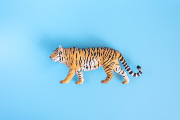 Fototapeta na wymiar the tiger, symbol of 2022 year. plastic orange toy figure tiger on a blue background. top view
