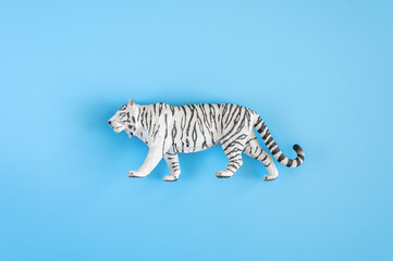 Fototapeta na wymiar the tiger, symbol of 2022 year. plastic white toy figure tiger on a blue background. top view