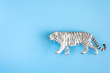 Fototapeta na wymiar the tiger, symbol of 2022 year. plastic white toy figure tiger on a blue background. top view. space for text