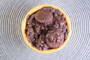 typical Brazilian food feijoada made with beans, pork, bacon, sausage with cabbage, rice, salad, spices and pepper.