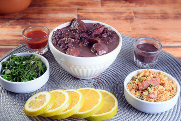 typical Brazilian food feijoada made with beans, pork, bacon, sausage with cabbage, rice, salad, spices and pepper.