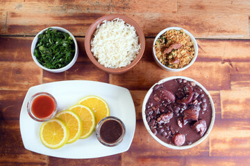 typical Brazilian food feijoada made with beans, pork, bacon, sausage with cabbage, rice, salad, spices and pepper.