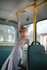 Naklejka premium a girl with short hair, in a baseball cap, in a dress, is riding alone on a bus, a beautiful girl with short hair, wearing a hat on the bus smiles