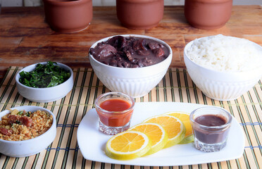 typical Brazilian food feijoada made with beans, pork, bacon, sausage with cabbage, rice, salad, spices and pepper.