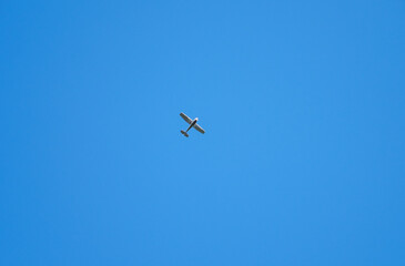 Single old retro glider high against the blue sky. Airplane flies in clear sky. Aircraft aviation.