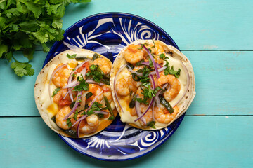 Mexican food. Shrimp tacos with melted cheese and poblano pepper called gobernador on turquoise background.