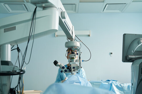 Ophthalmologist looking through microscope during eye operation in clinic