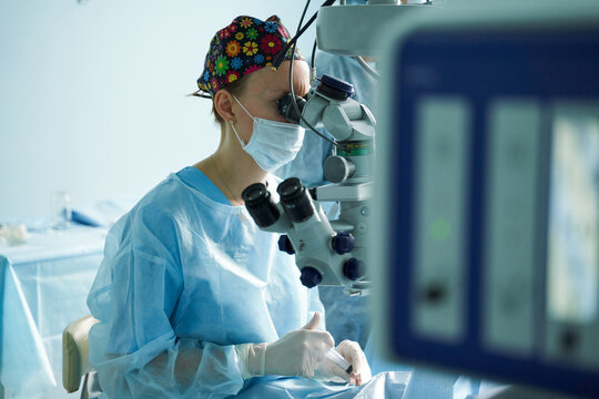 Ophthalmologist looking through microscope during eye operation in clinic