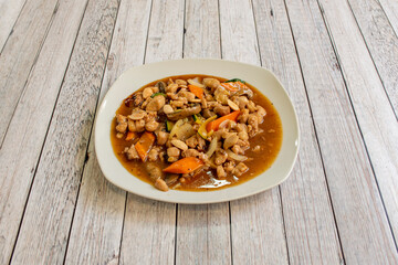 Chinese dish popular in European restaurants of chicken with almonds and carrots sauteed with onion, zucchini and mushrooms on white table