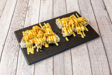sushi uramaki tempura roll with lots of sauce and prawns in tempura with soy sauce