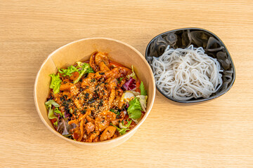 Korean yeyuk with sweet potato noodles in a home delivery container on wooden table