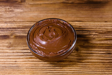 Glass bowl with chocolate spread on a wooden table