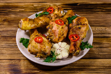 Baked chicken legs with parsley, garlic and sliced red hot pepper in a plate